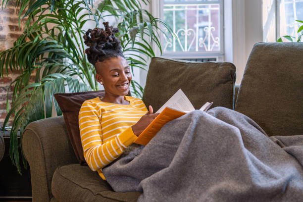 Black woman reading a book and relaxing on the couch
